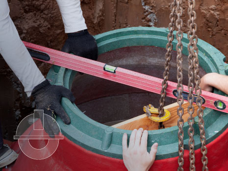 Two people working on installation of underground tank for sewage system