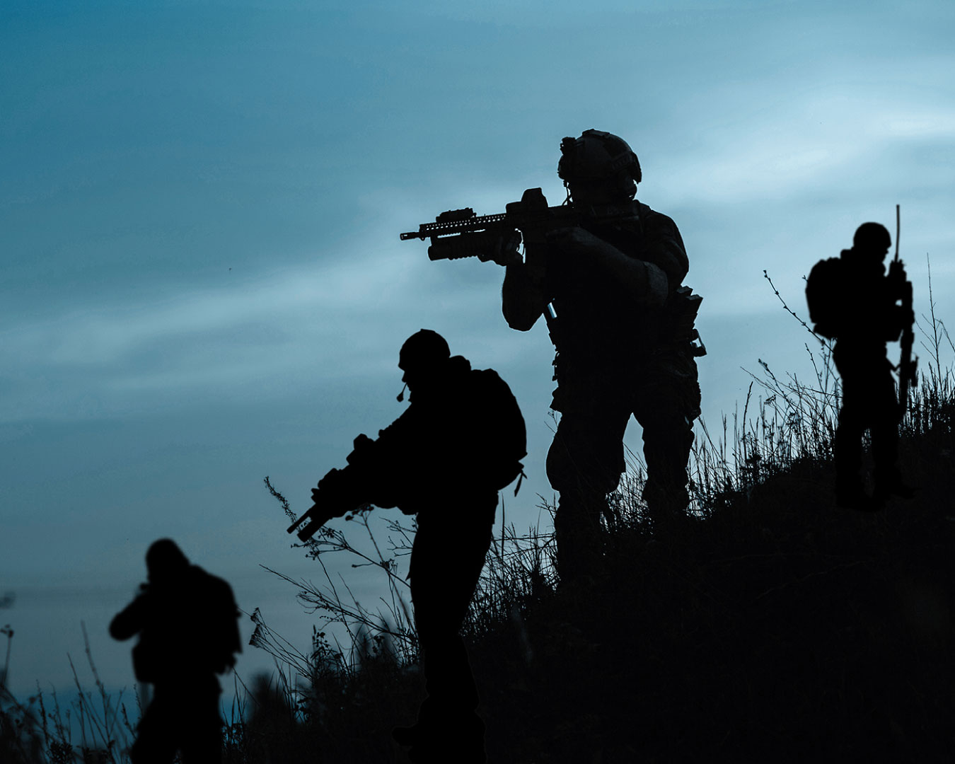 Silhouette of military soldier or officer with weapons at night. shot, holding gun, blue colorful sky, background