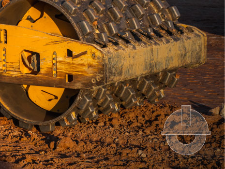 Soil compactor with vibratory padfoot drum. Heavy duty machinery working on highway construction site. Vehicle for soil compaction. Road construction equipment. Paving. Compaction of the road.