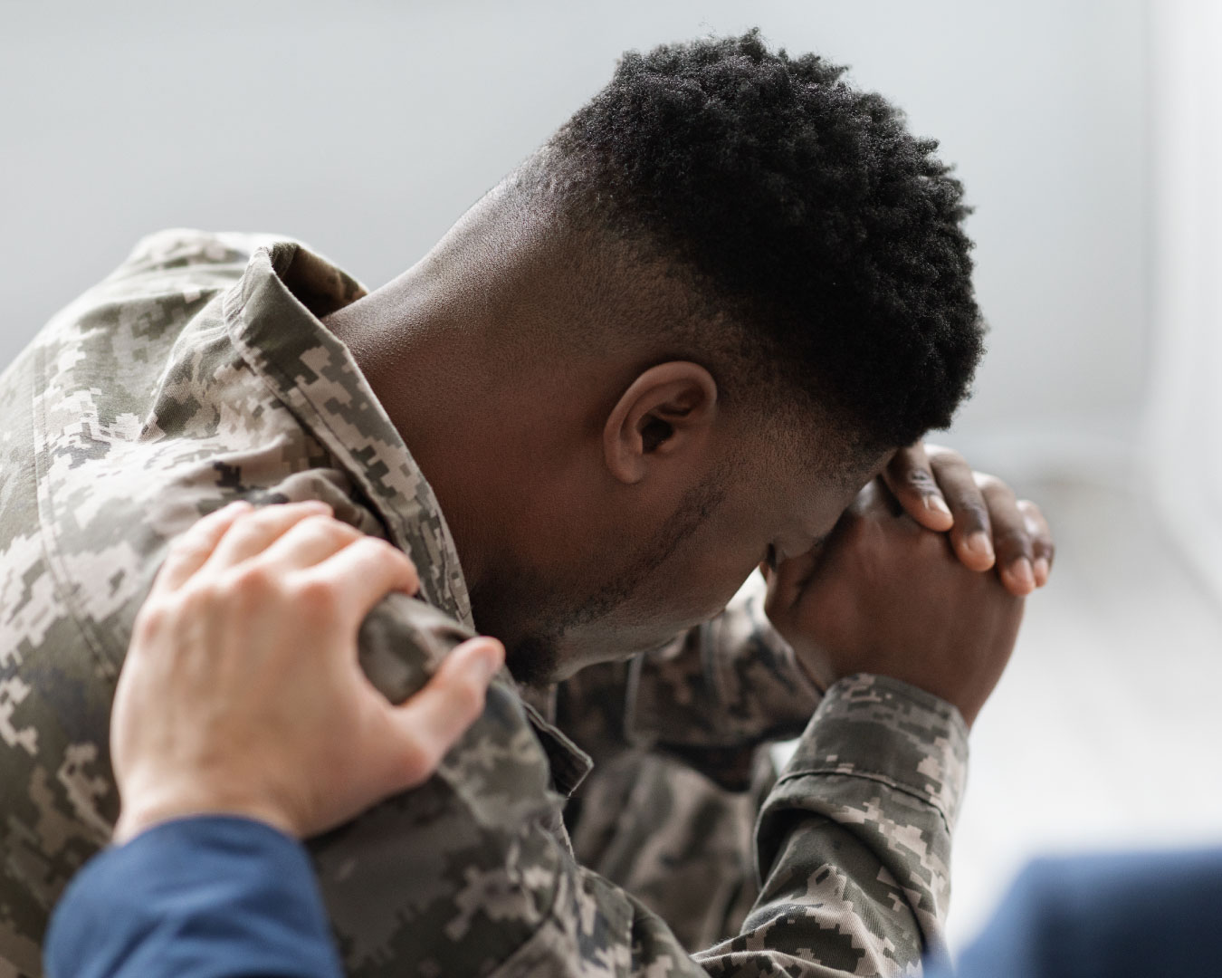 Unrecognizable man placing hand on black soldier shoulder for comfort