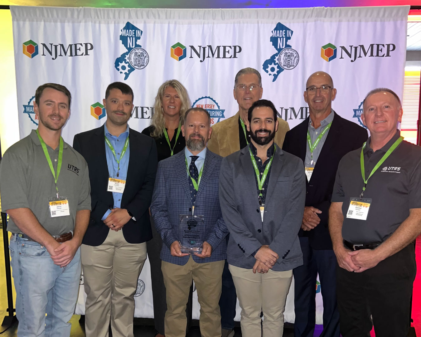 The UTRS Advanced Manufacturing LLC leadership team with the 2025 ‘MADE in New Jersey’ Manufacturing Day Manufacturer of the Year – MEDIUM award. Picture (l-r): James Stanger, Nolan Oullette, Julie Gaum, Pat Napolitano (holding award), Tom Weiss, Rob Handelman, Ken Hunter, and Gordon MCneill.