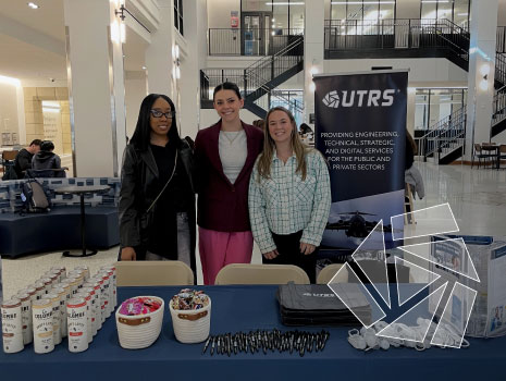 Pictured are three UTRS HR employees standing at the UTRS branded booth in the Jones Family Learning Commons at Villanova University