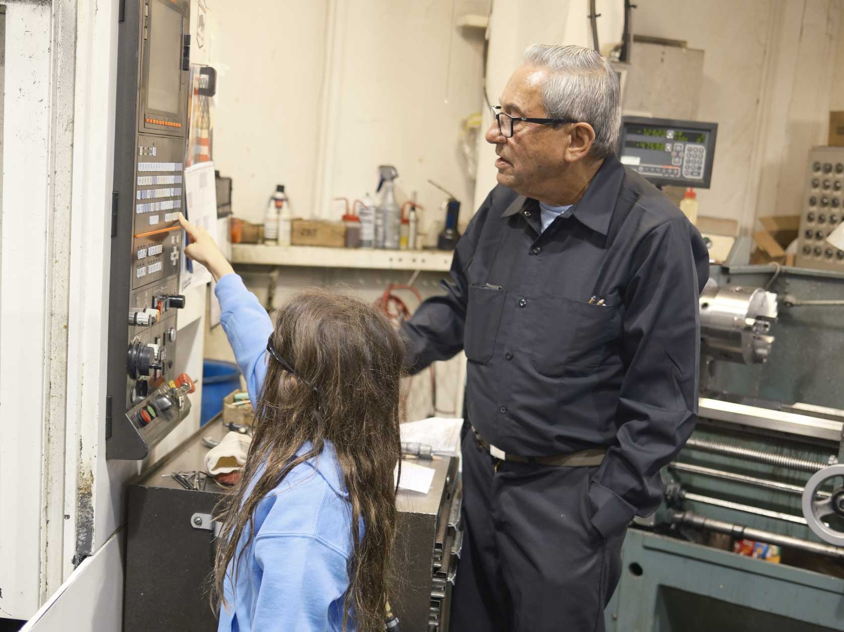 A child learns how CNC machines operate from a UTRS Advanced Manufacturing machinist.