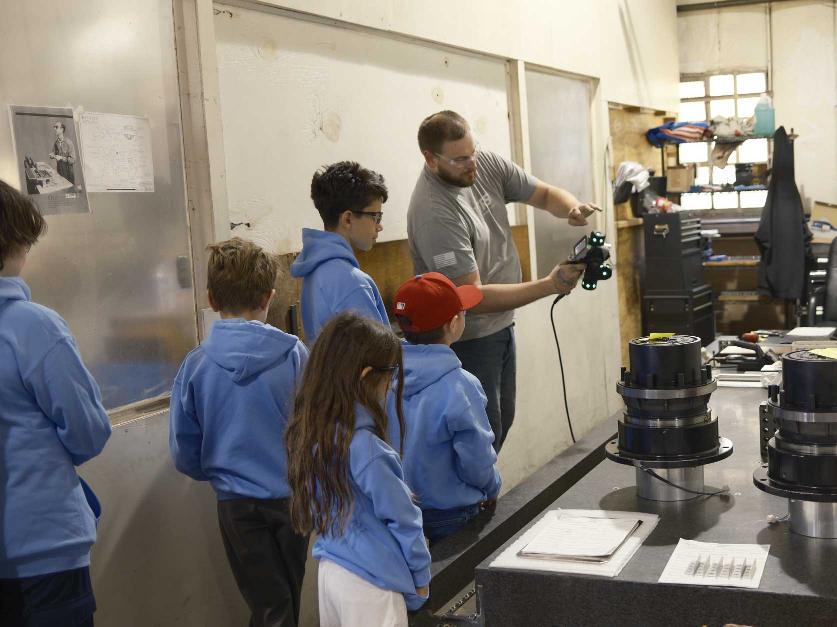 Children learning from a UTRS Advanced Manufacturing quality control engineer how the Keyence WM-series Wide Area CMM and 3D Scanner can be used to examine or reverse engineer complex parts.