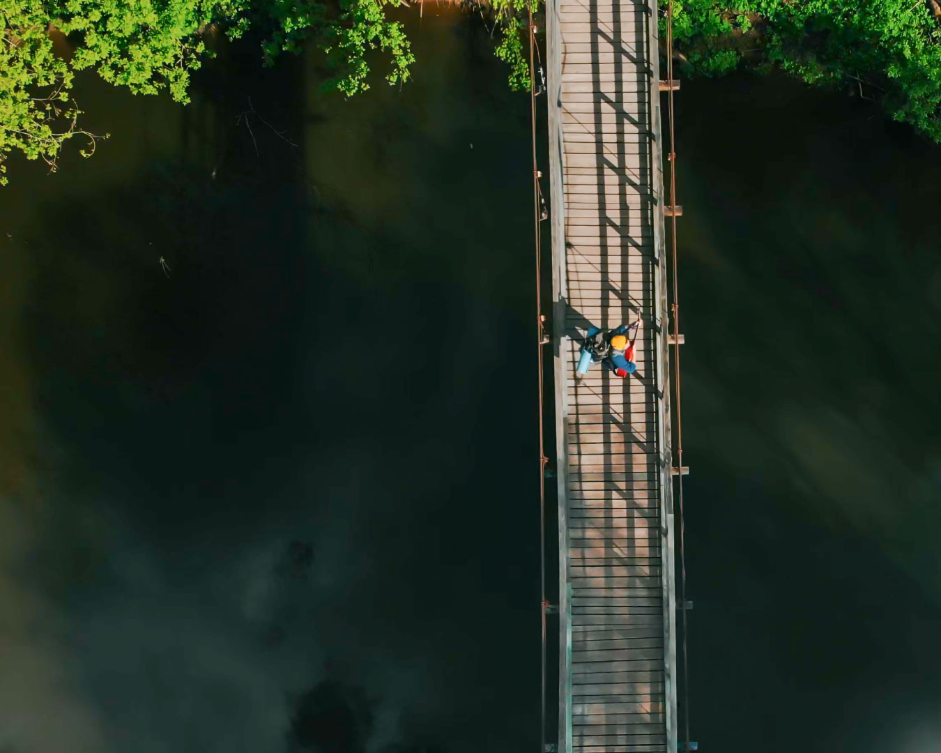 A person walking on the rope bridge in the forest. Aerial view
