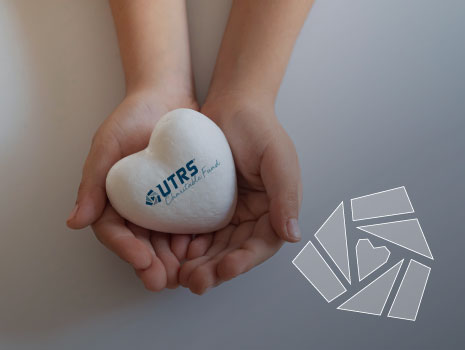 Person holding white heart with UTRS Charitable Fund Logo on heart in palm.